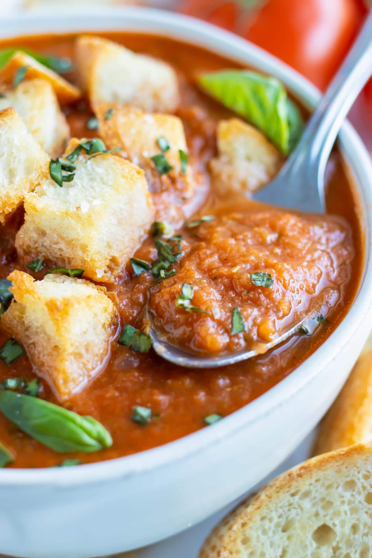 A spoon scooping out a bite of a thick and creamy roasted tomato soup recipe.