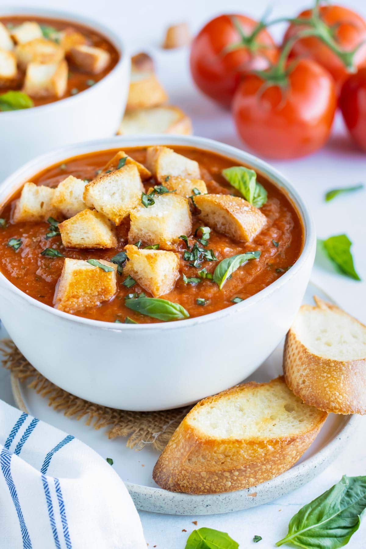 A soup bowl full of creamy roasted tomato basil soup with homemade croutons.