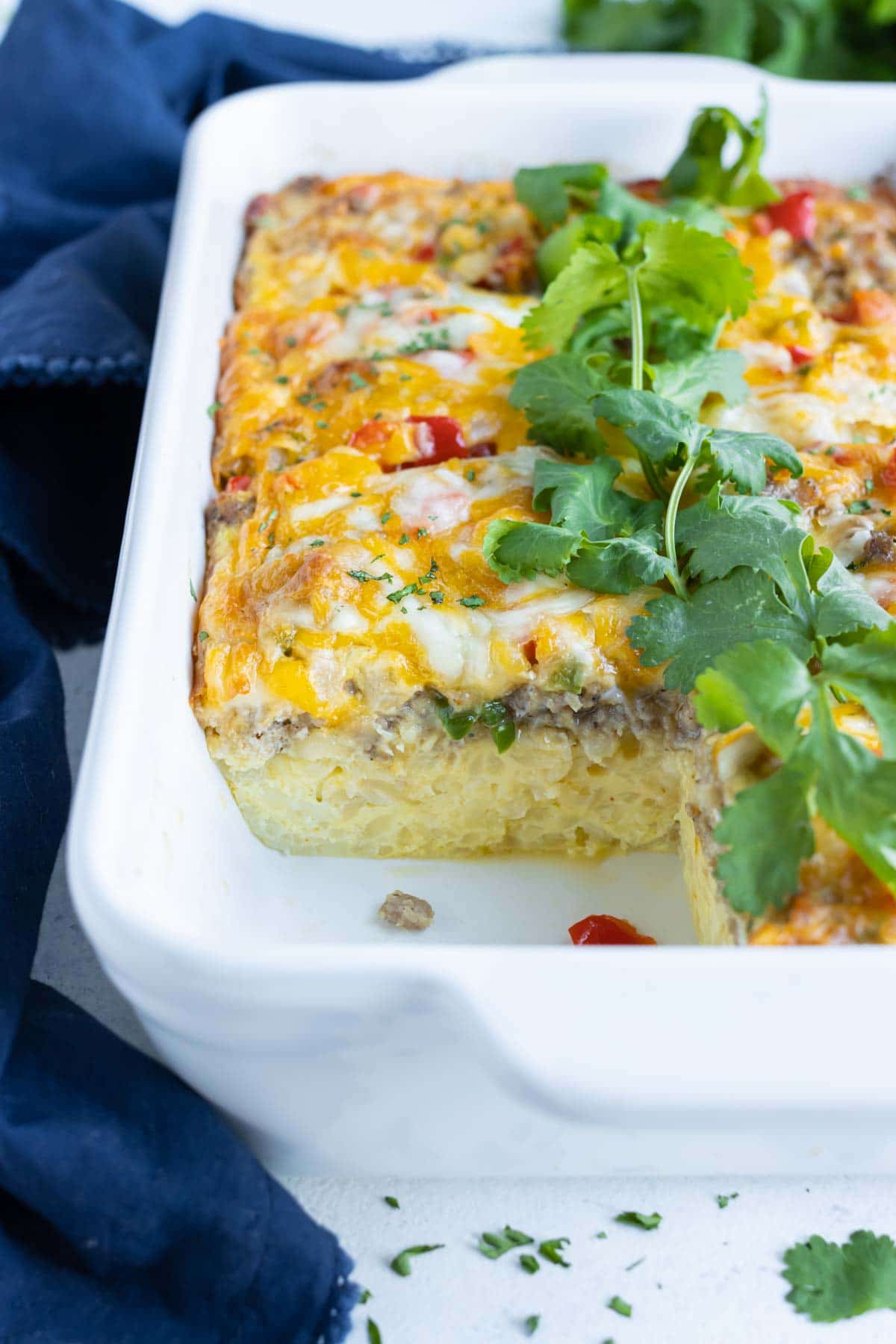 A serving of breakfast casserole is removed from the baking dish.