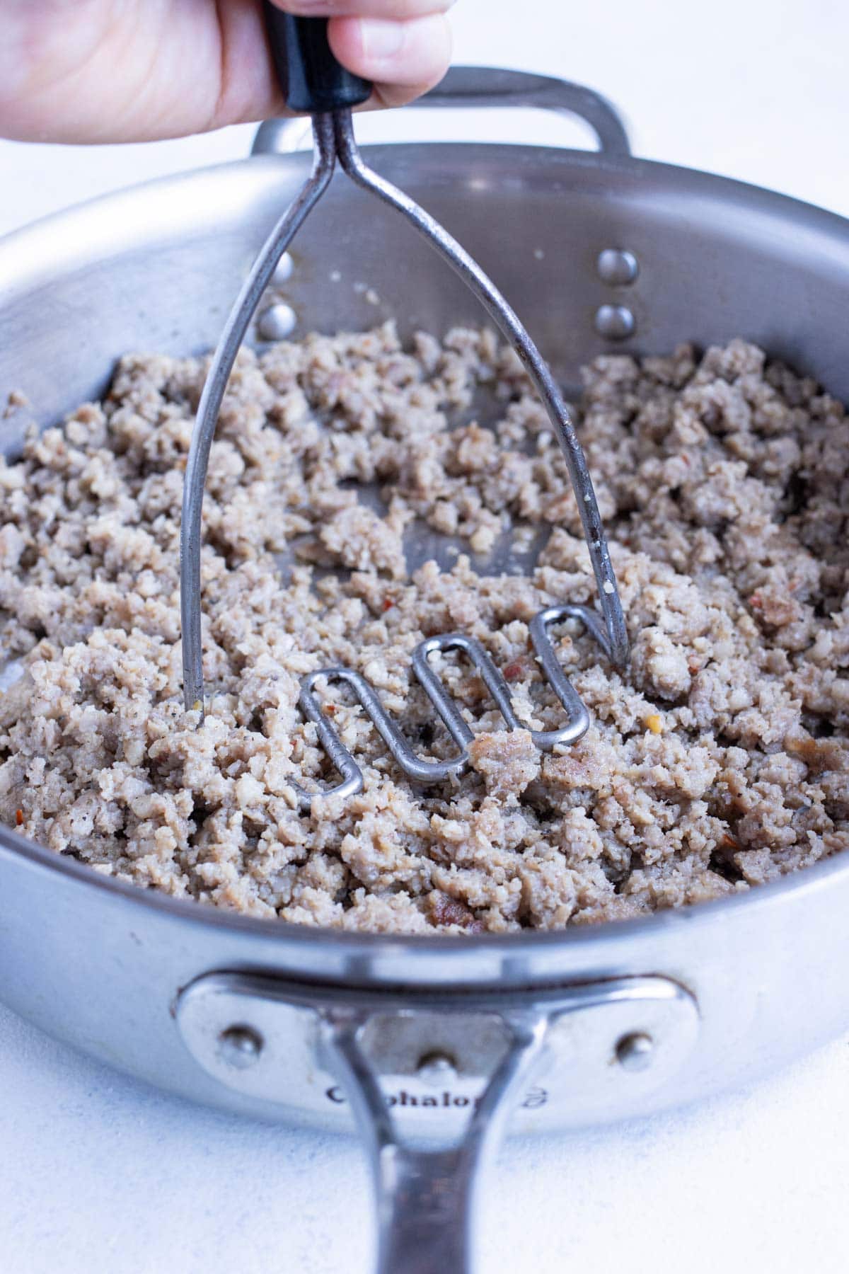 Ground sausage is cooked on the stove.