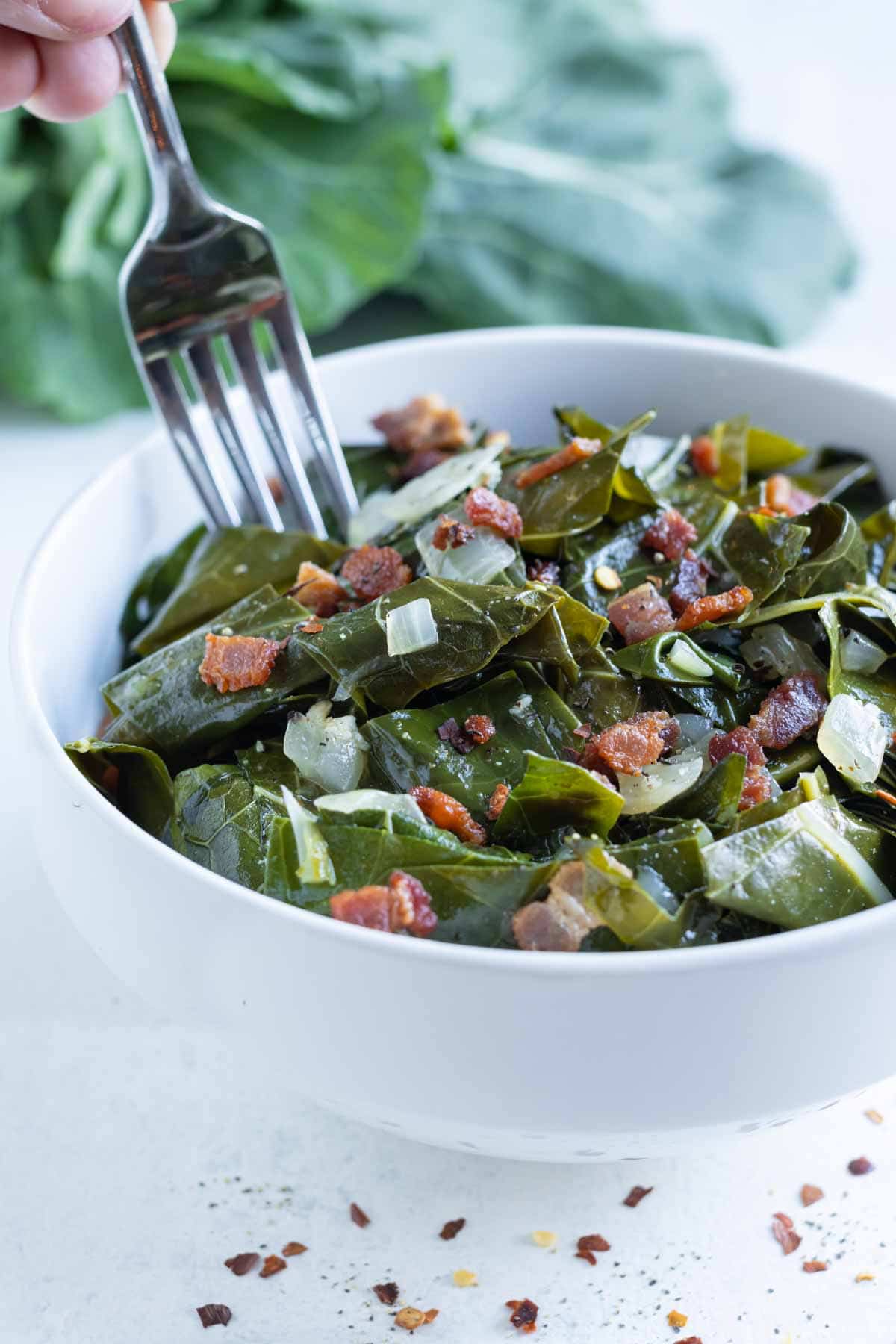 A fork is shown eating collard greens.