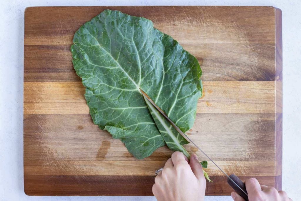 The rib of the collard greens is removed with knife.