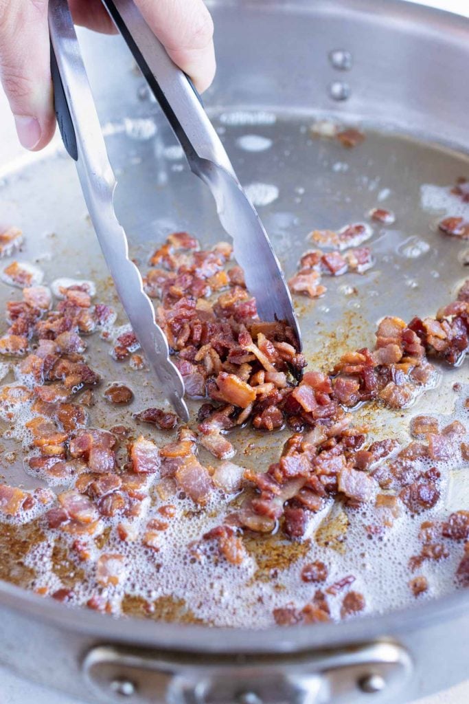 Chopped bacon is cooked on the stove.
