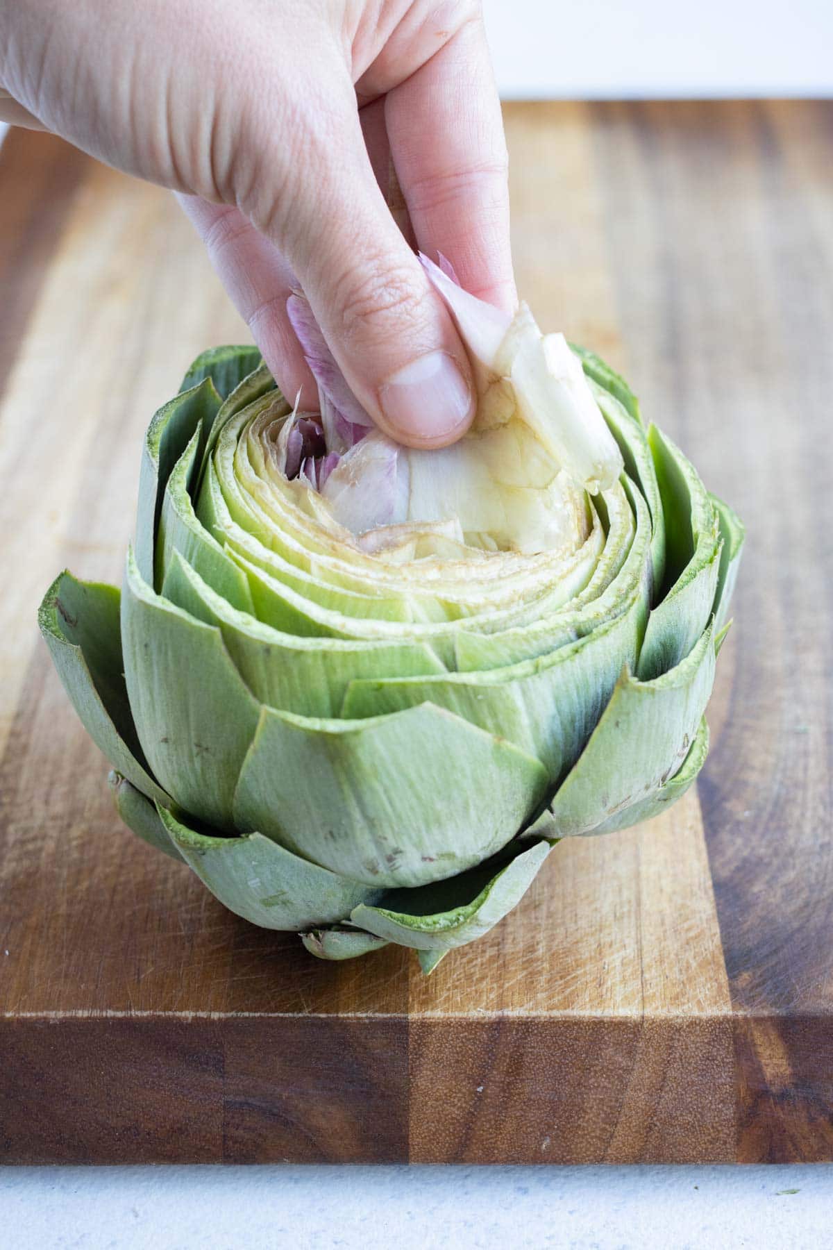 Feathery leaves from the artichoke center is taken out by hand.