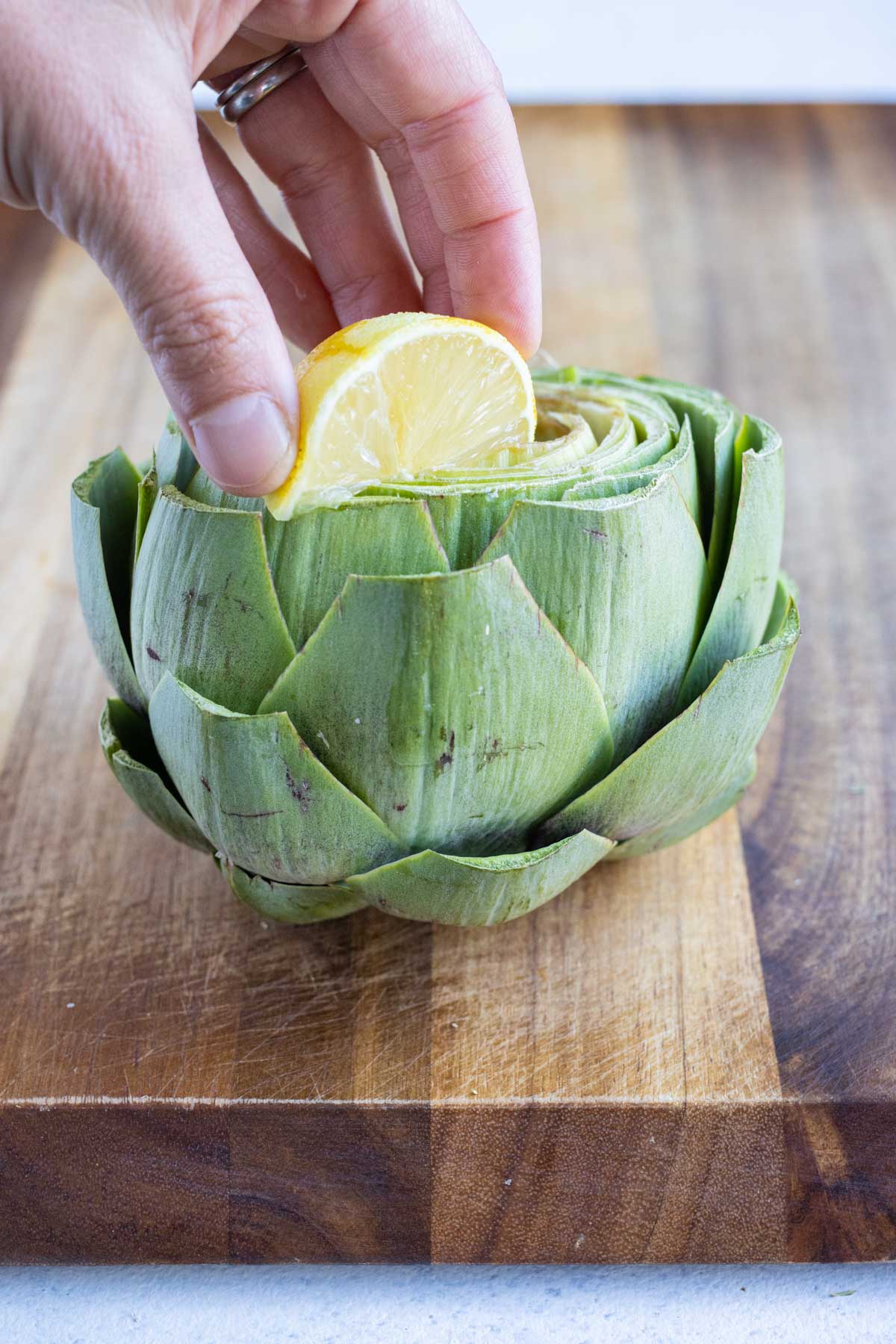 Lemon juice is squeezed on top of the stuffed artichoke.