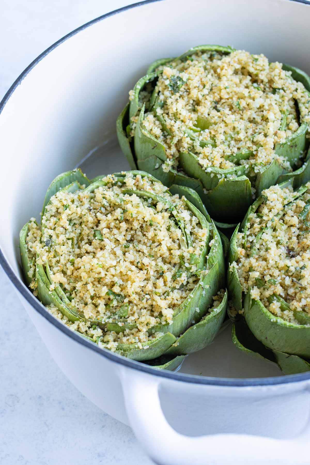 Stuffed artichokes are cooked in the oven in a dutch oven.