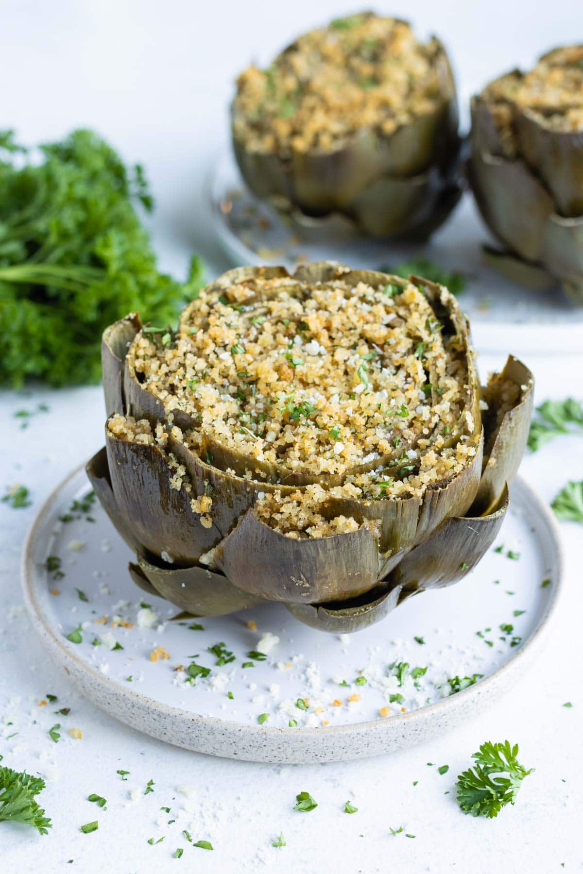 Easy stuffed artichokes are served on a white plate.