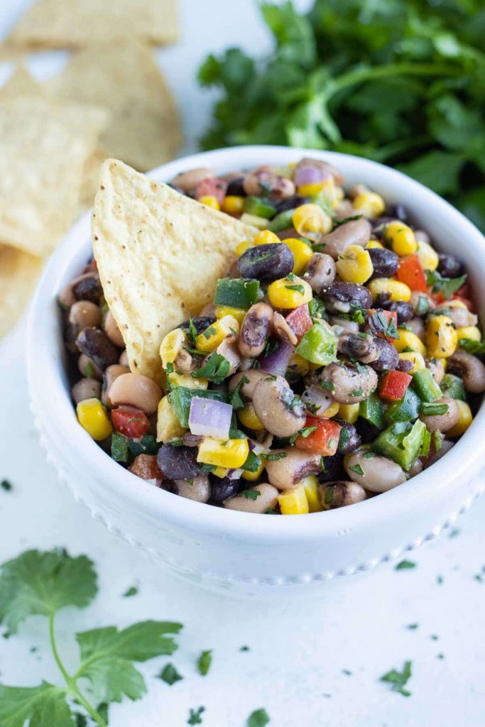 A bowl is filled with cowboy caviar and served with chips.