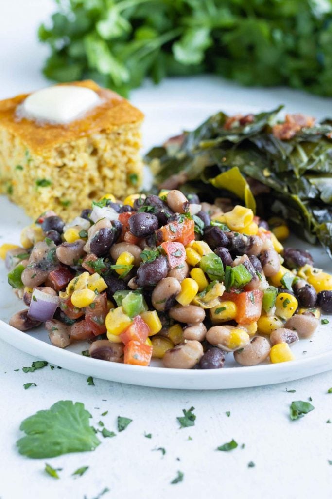 A plate is filled with collard greens, cornbread, and Texas caviar.