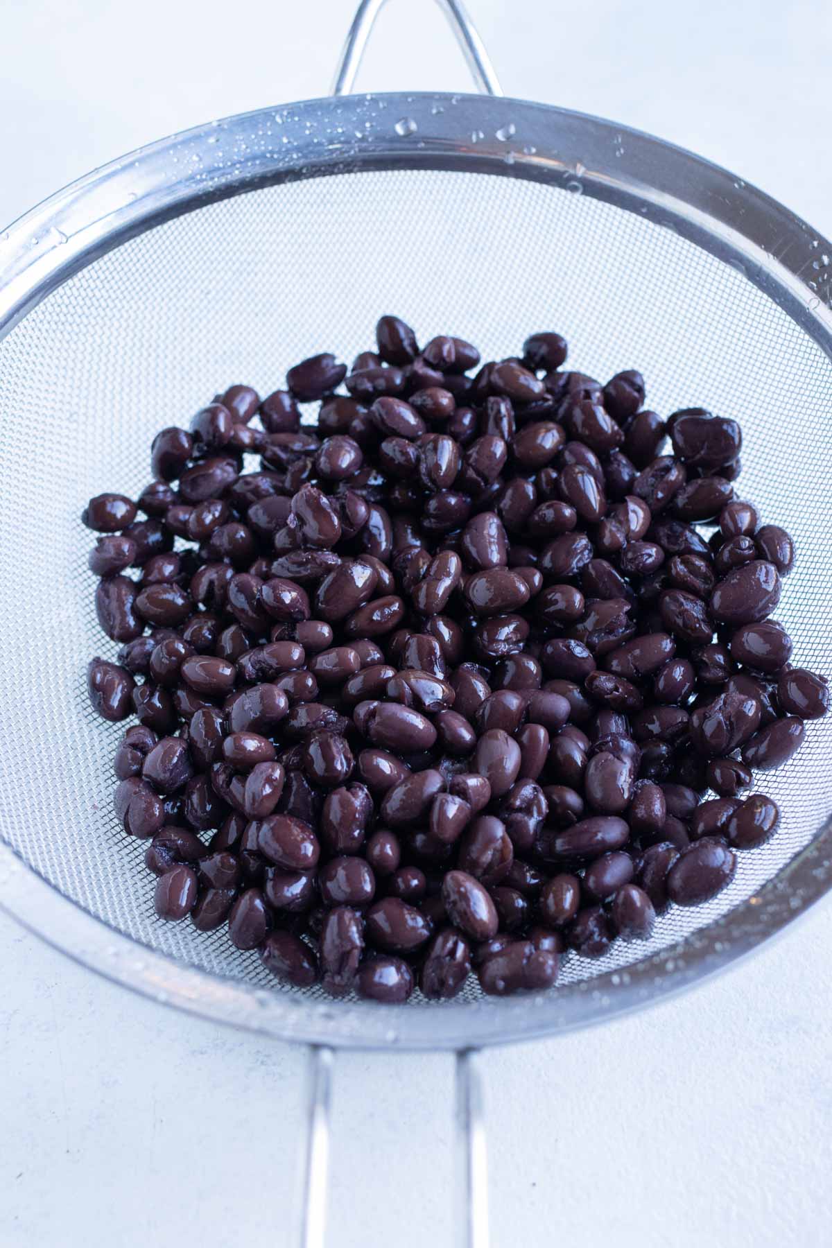 Black beans are rinsed in a colander.