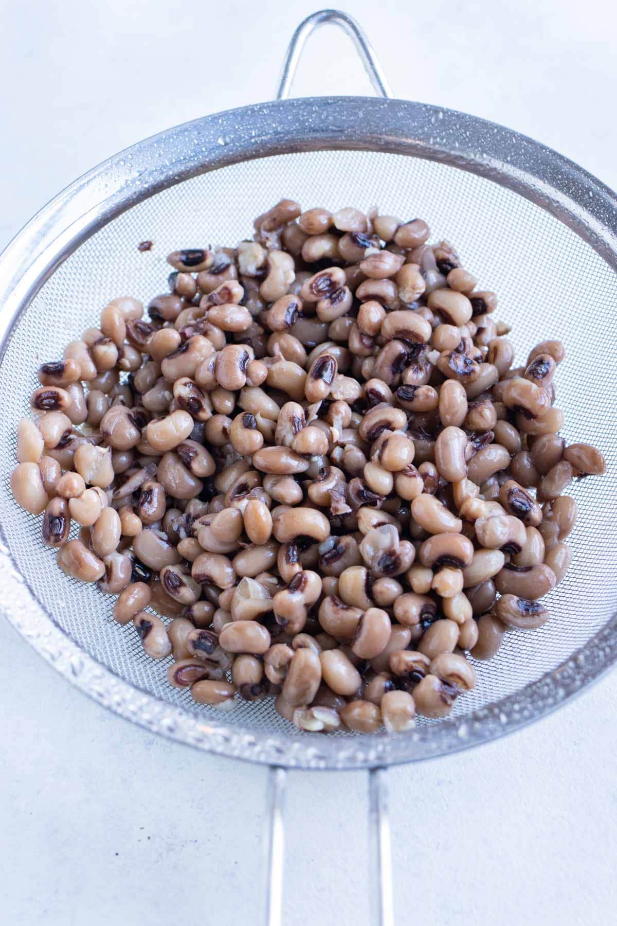 Black eyed peas are rinsed in a colander.