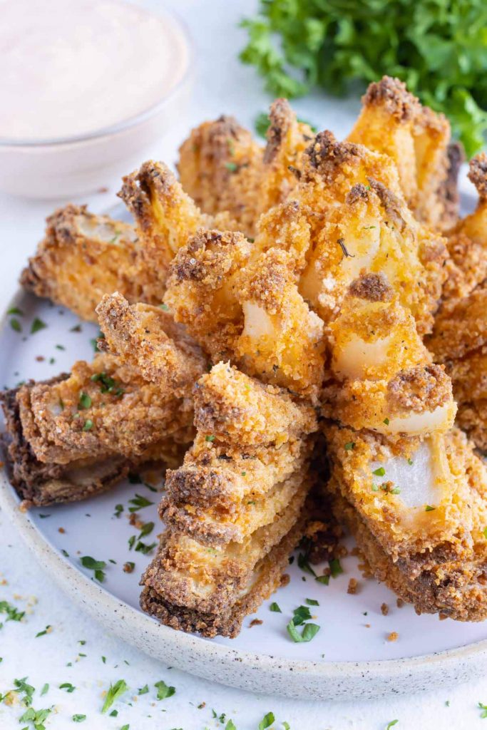 Easy fried onion is served on a plate with blooming onion sauce.