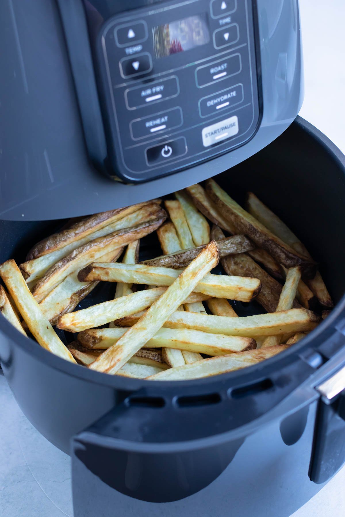 Crispy, cooked fries in the basket of an air fryer.