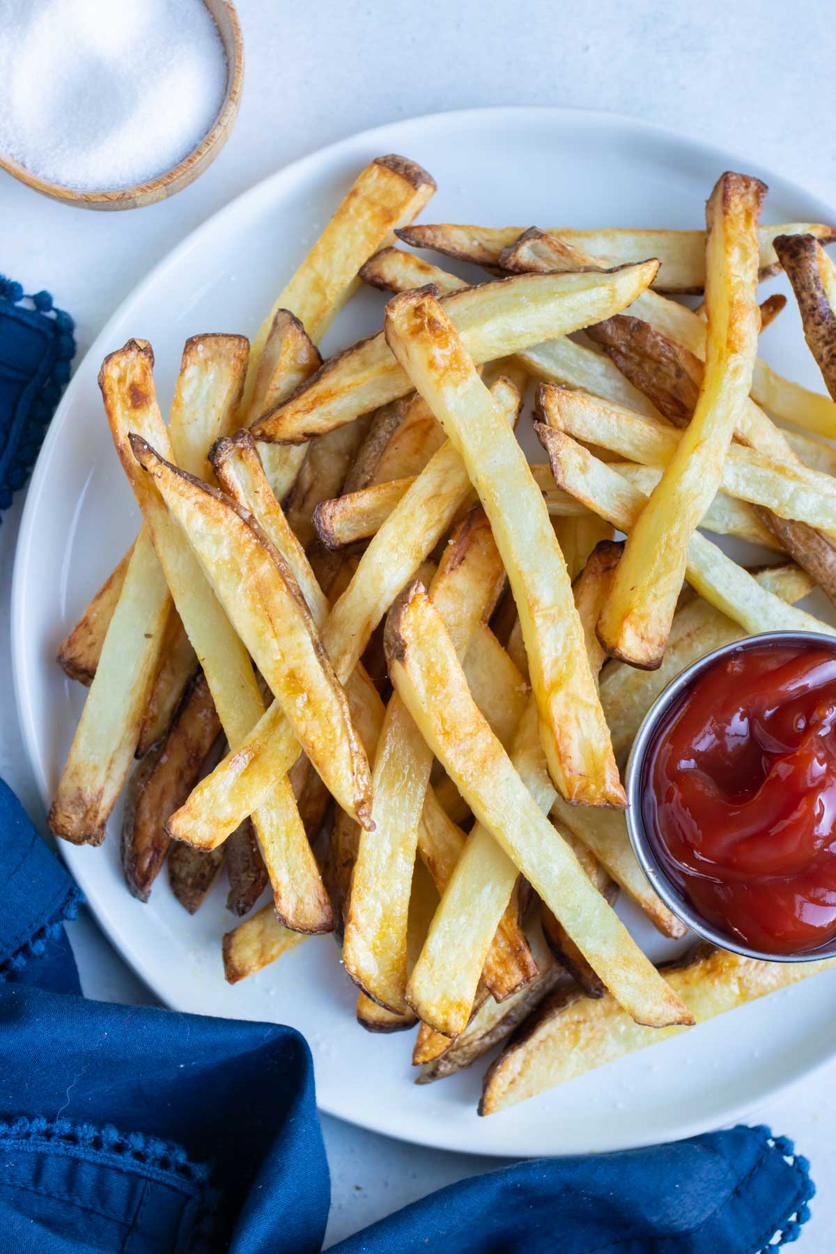 Air fryer french fries are served with ketchup on a white plate.