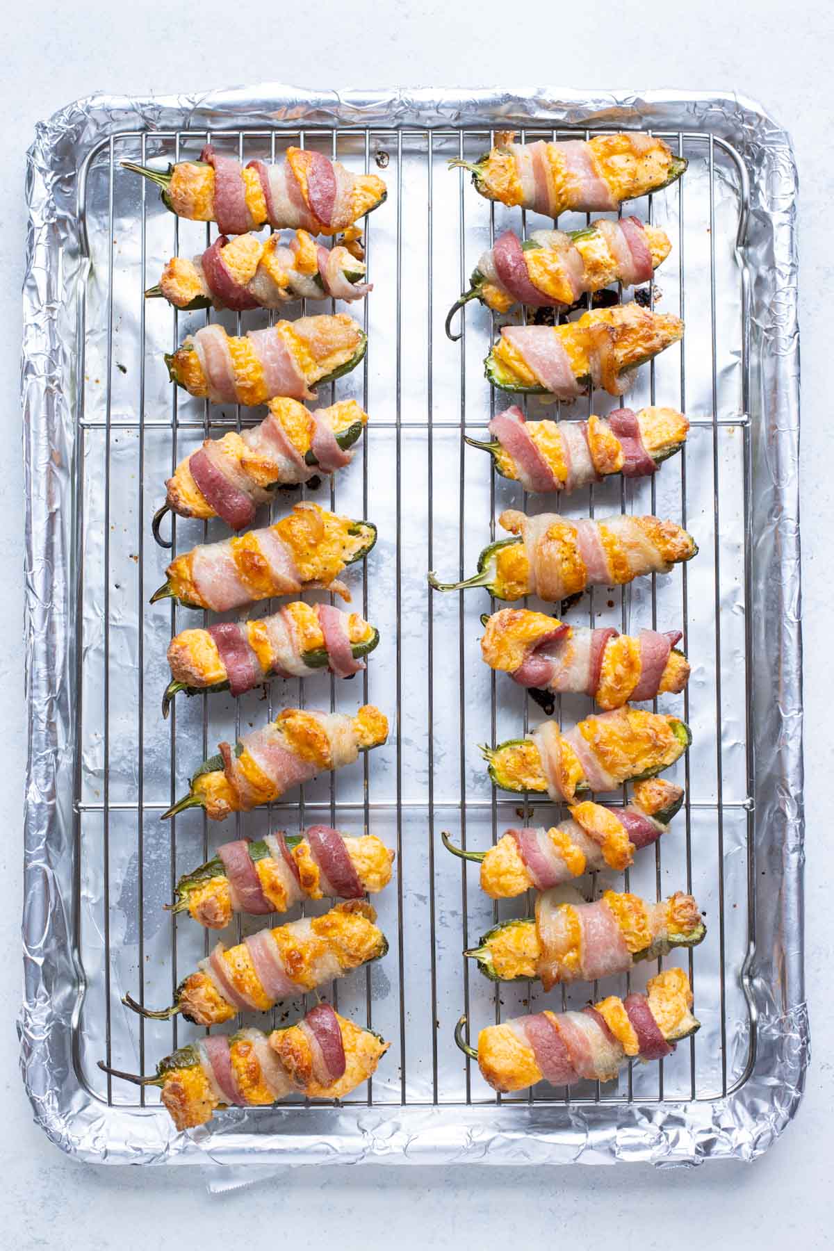 Bacon wrapped jalapeno poppers are cooked in the oven until golden brown.