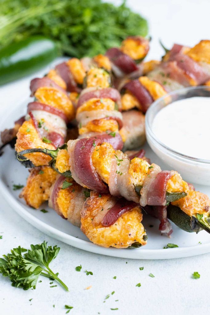 A plate is used to serve bacon jalapeno poppers with dip.
