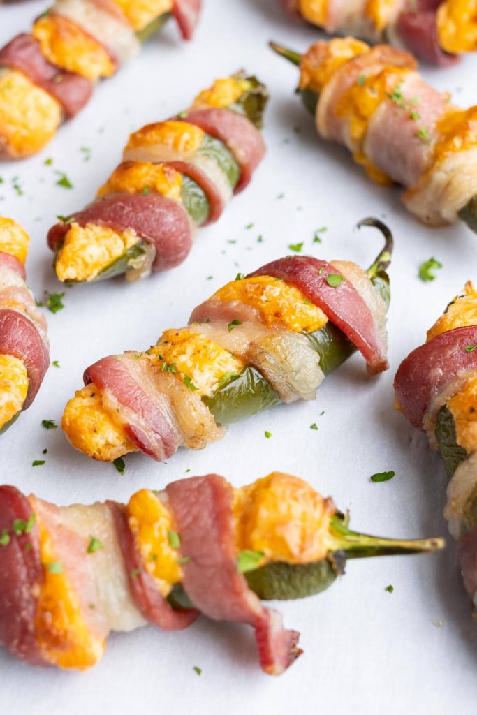 Bacon wrapped jalapeno poppers are topped with parsley before serving.