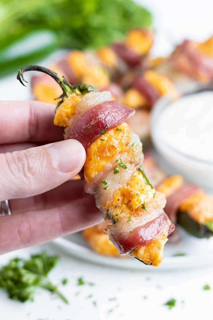 A hand is used to hold the golden jalapeno popper for a gluten-free snack.