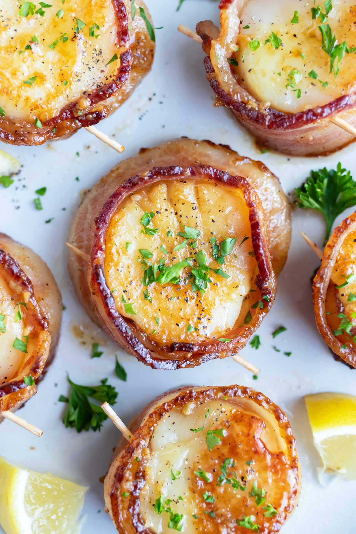 A serving plate full of bacon wrapped scallops for a dinner party appetizer or fancy seafood dinner date.
