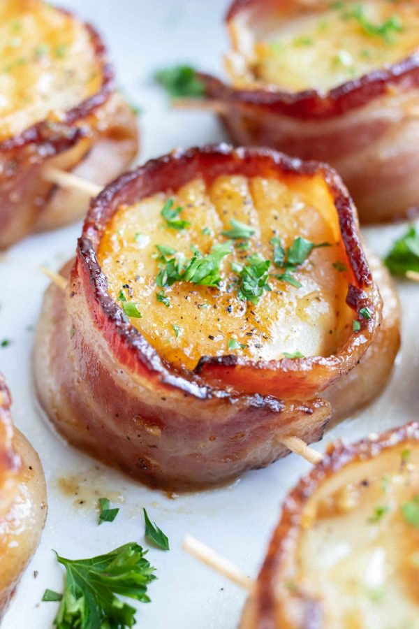 A large bacon wrapped scallop with parsley as a garnish.