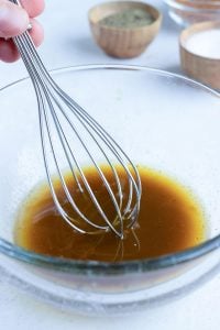 A hand whisking a brown liquid.