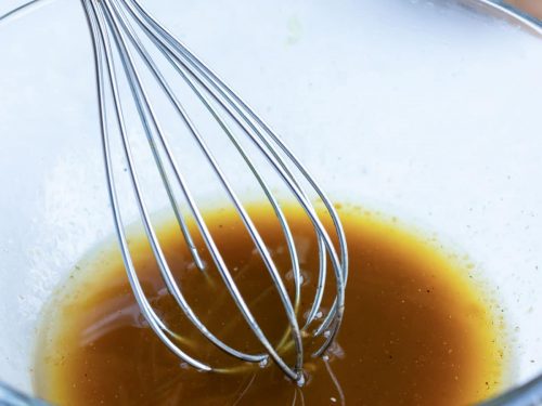 A hand whisking a brown liquid.