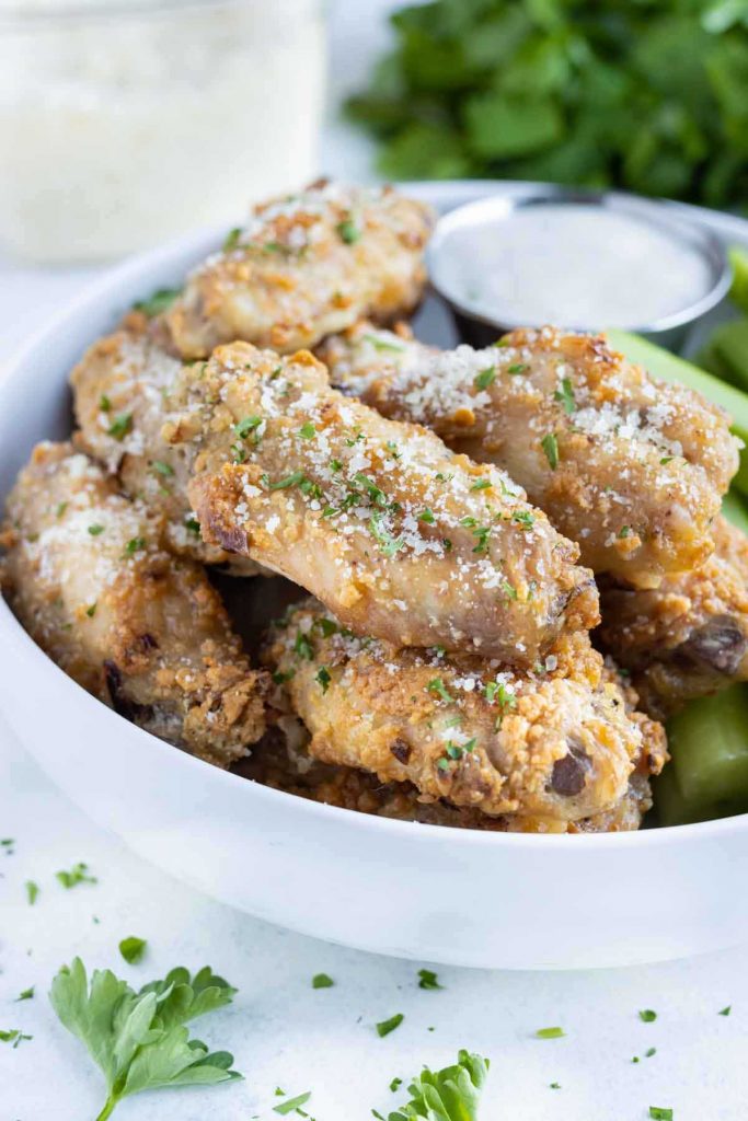 Crispy oven-baked chicken wings are served on a white plate with ranch.