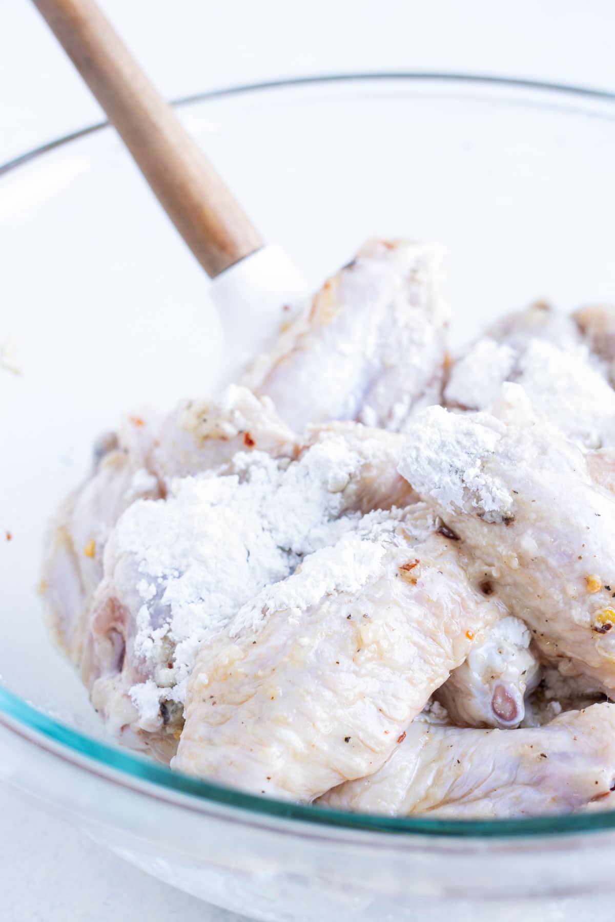 Cornstarch and parmesan are added to the bowl of wings.