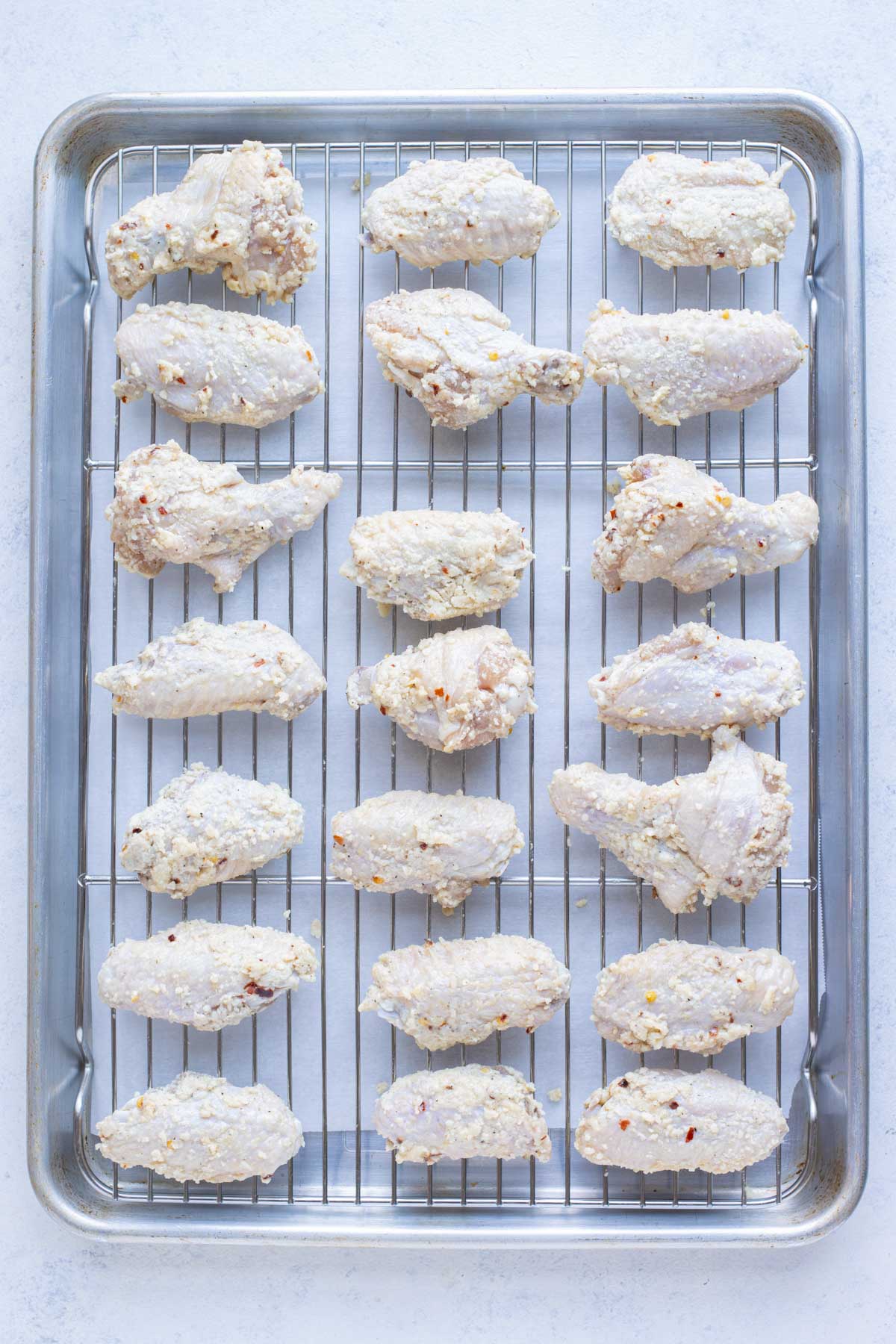 Oven-baked wings are placed on a wire rack before baking.