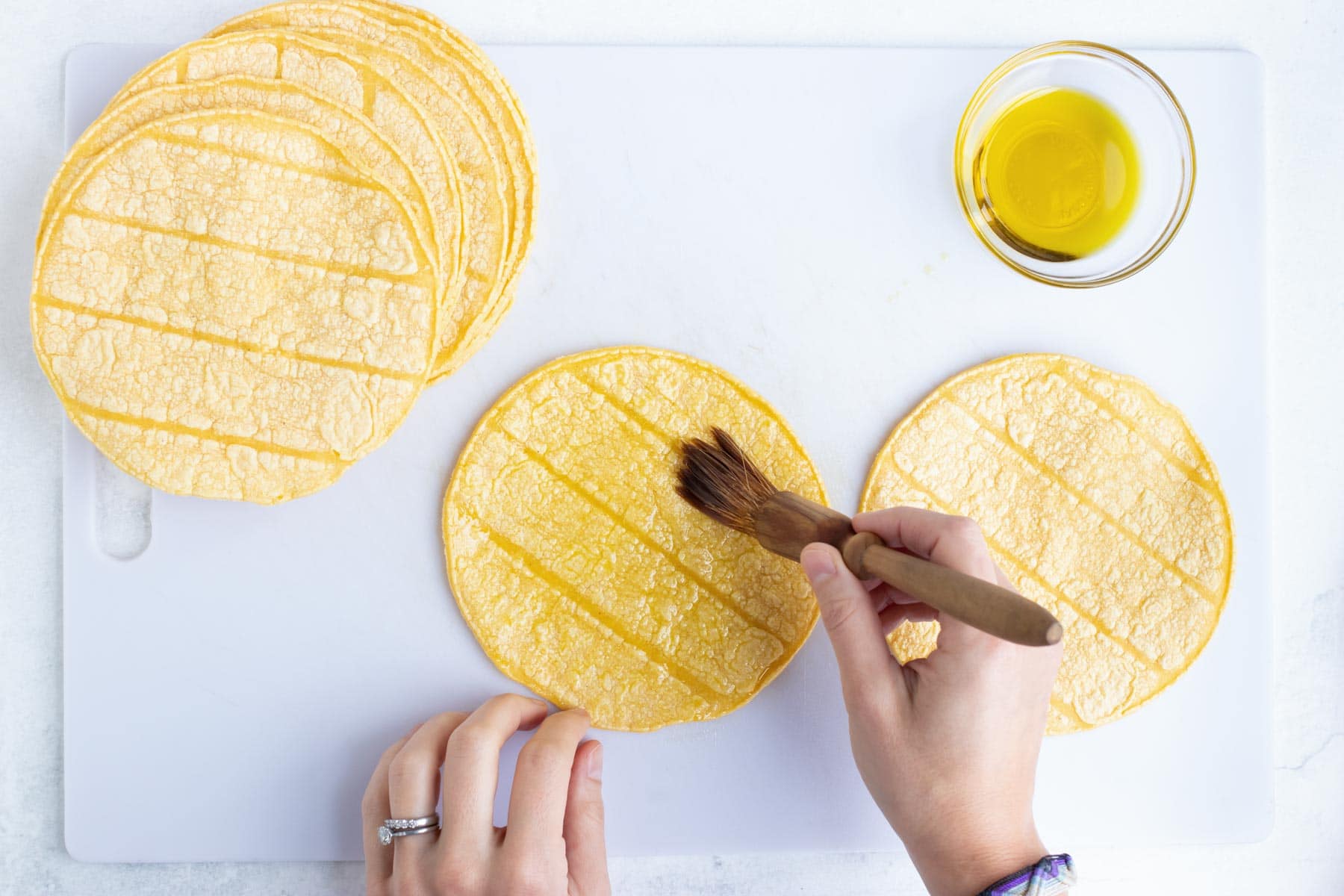 oil being brushed onto corn tortillas