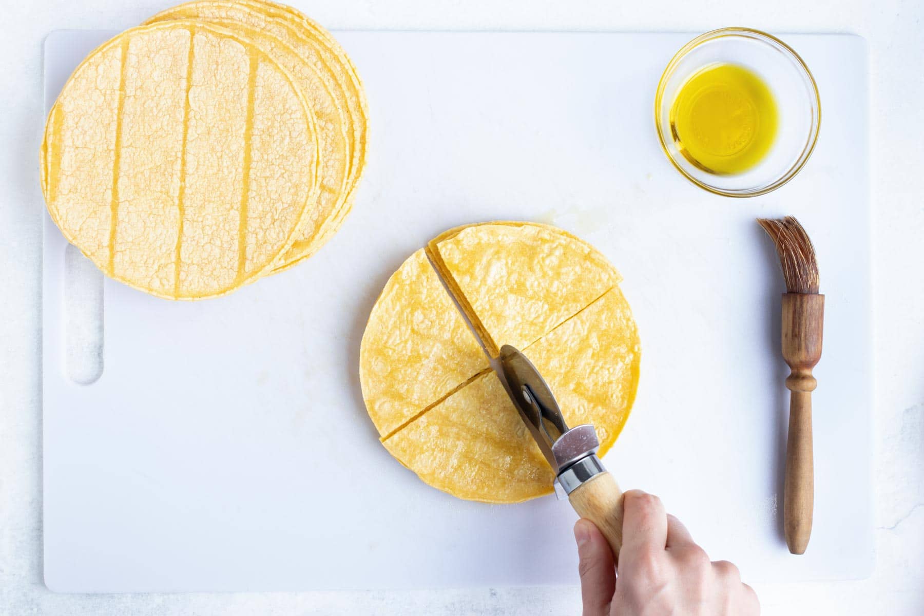 Tortillas being cut with a pizza cutter.