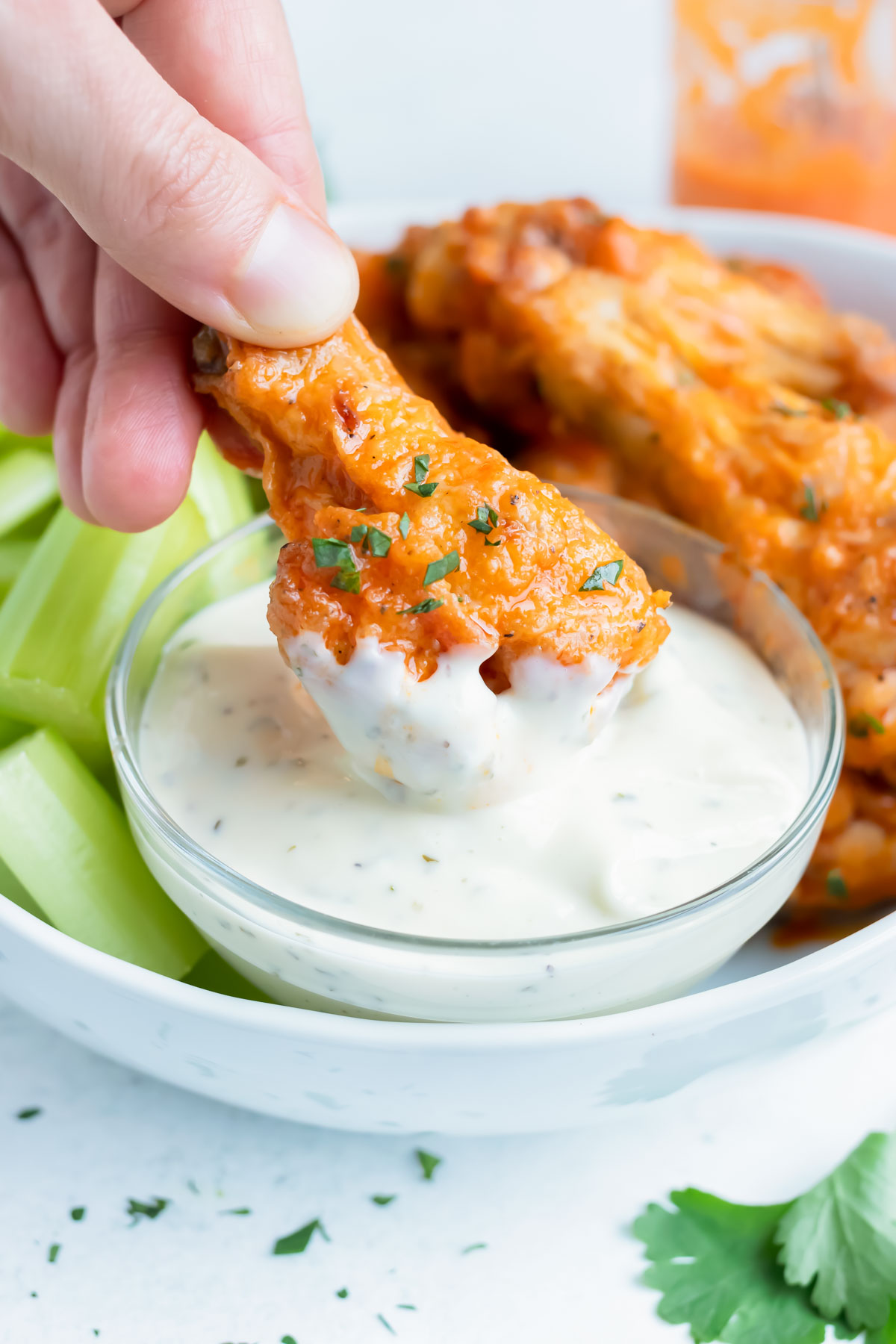 A buffalo chicken wing is dipped in ranch dressing.