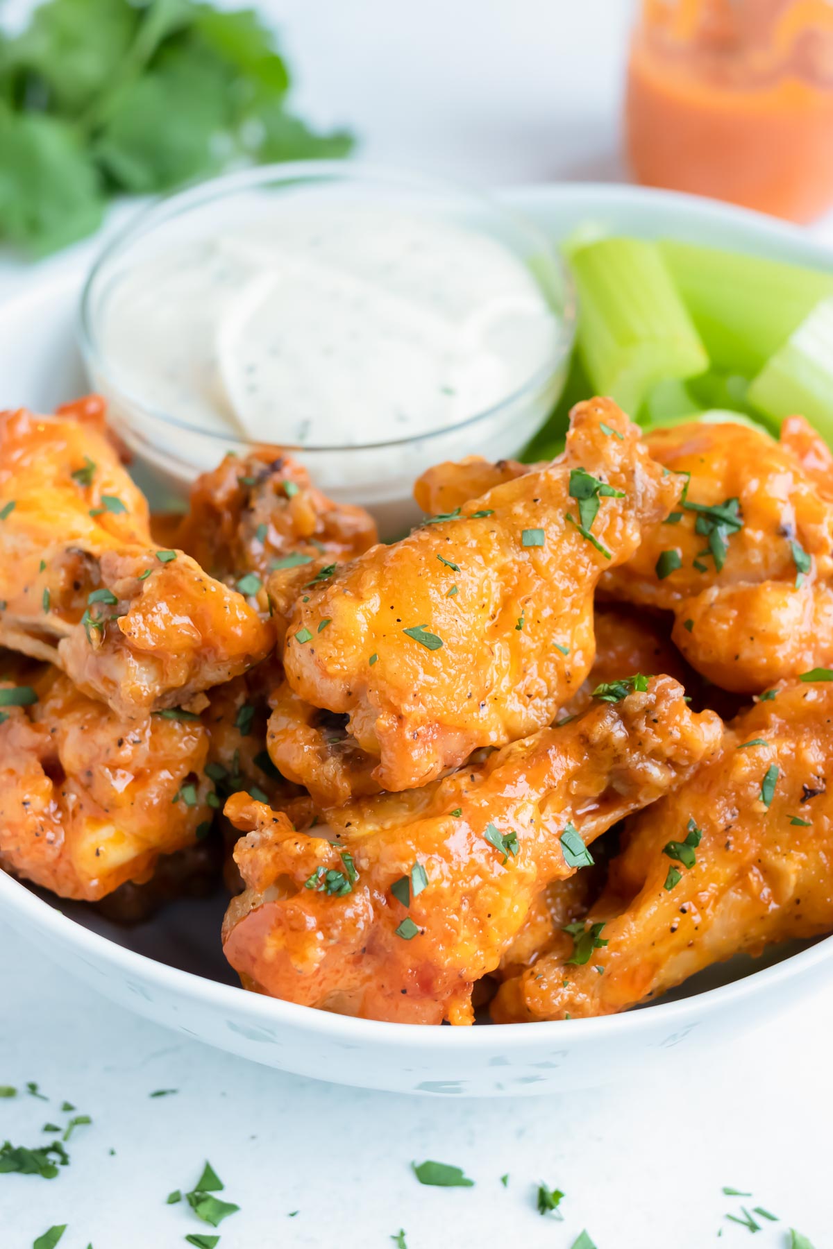 Crispy buffalo wings are served on a plate with celery and ranch.