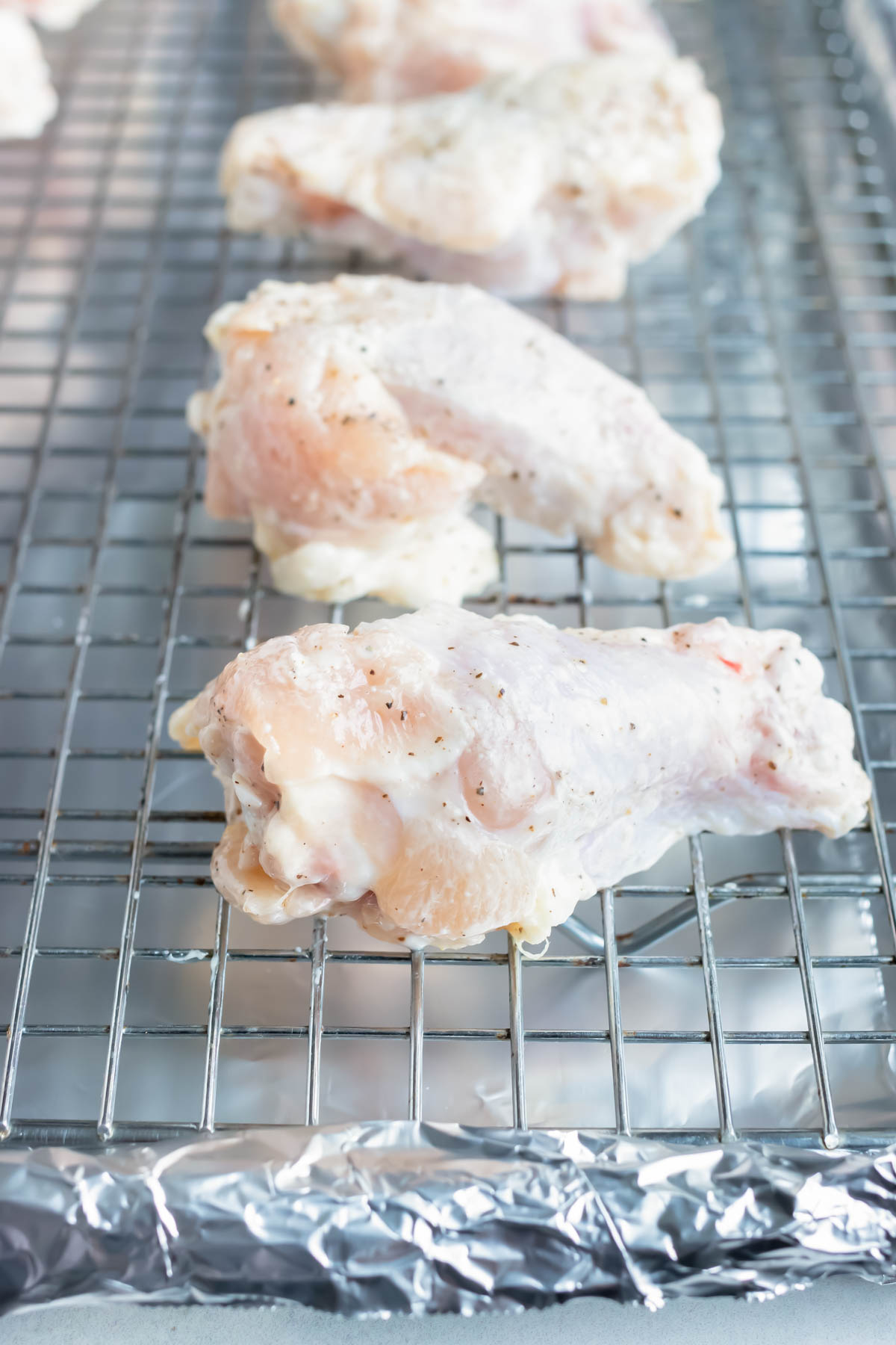 Cornstarch covered chicken wings are placed on a baking sheet.