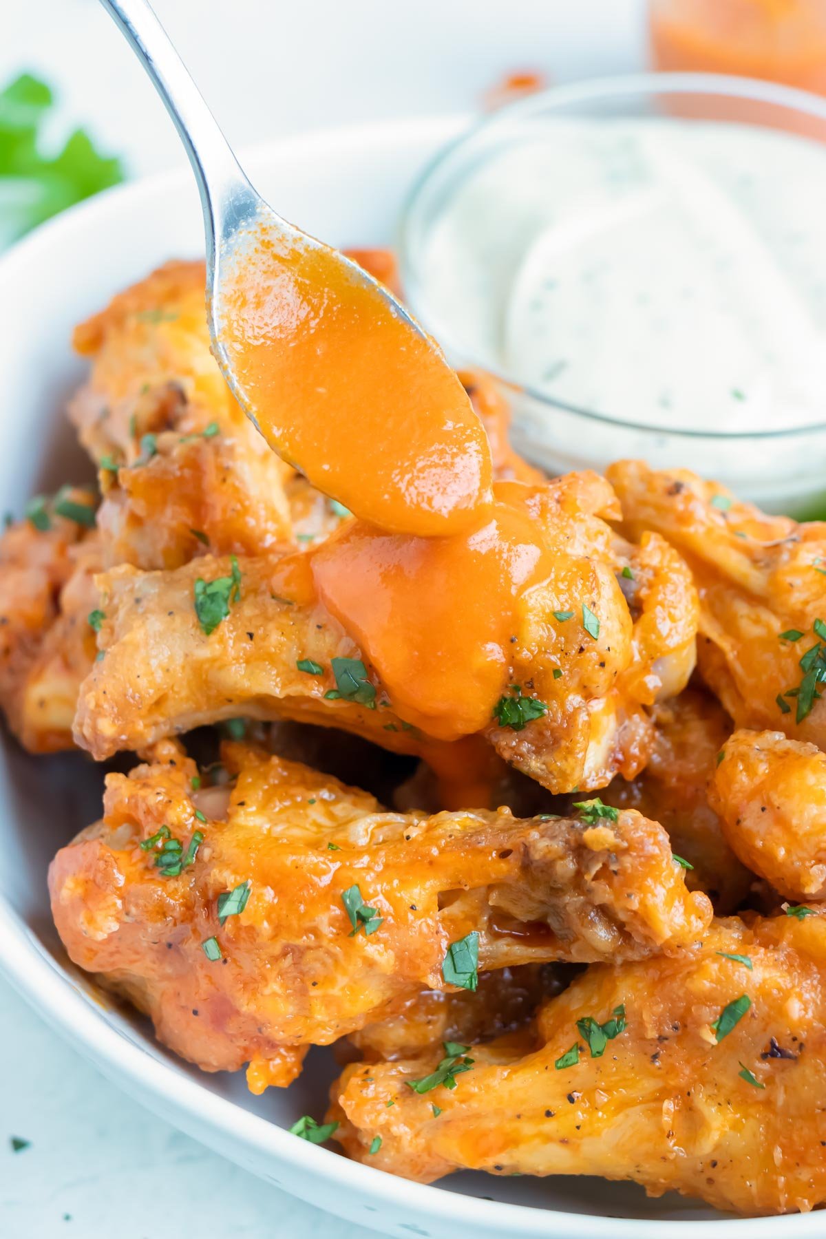 Buffalo sauce is poured on chicken wings.