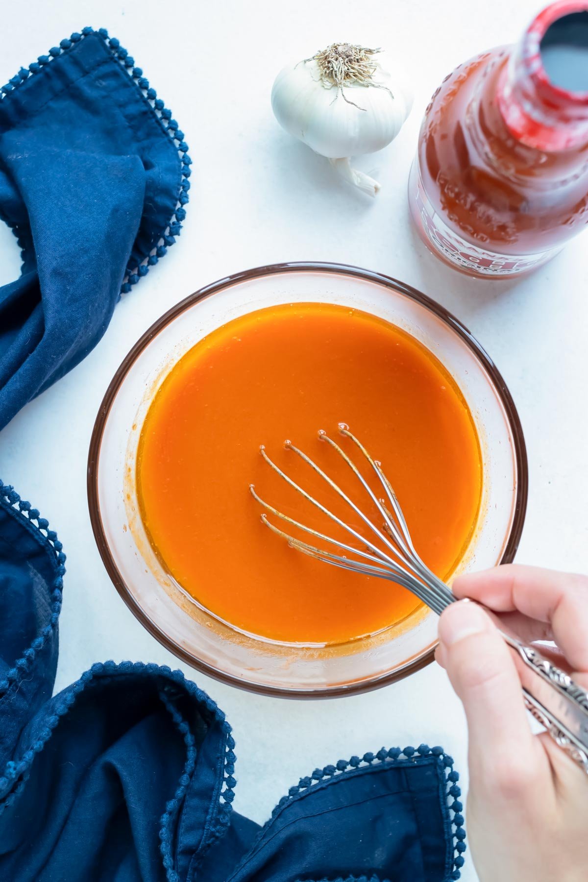 Homemade buffalo sauce is made in a glass bowl.