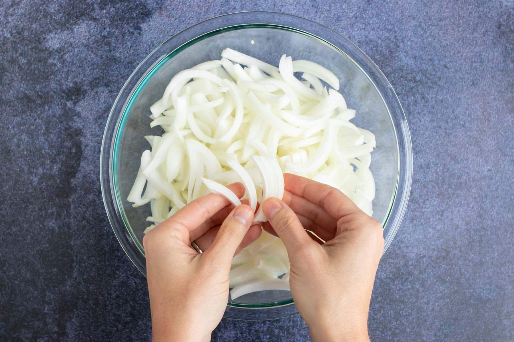 A bowl full of onions that are being separated for a caramelized onions recipe.