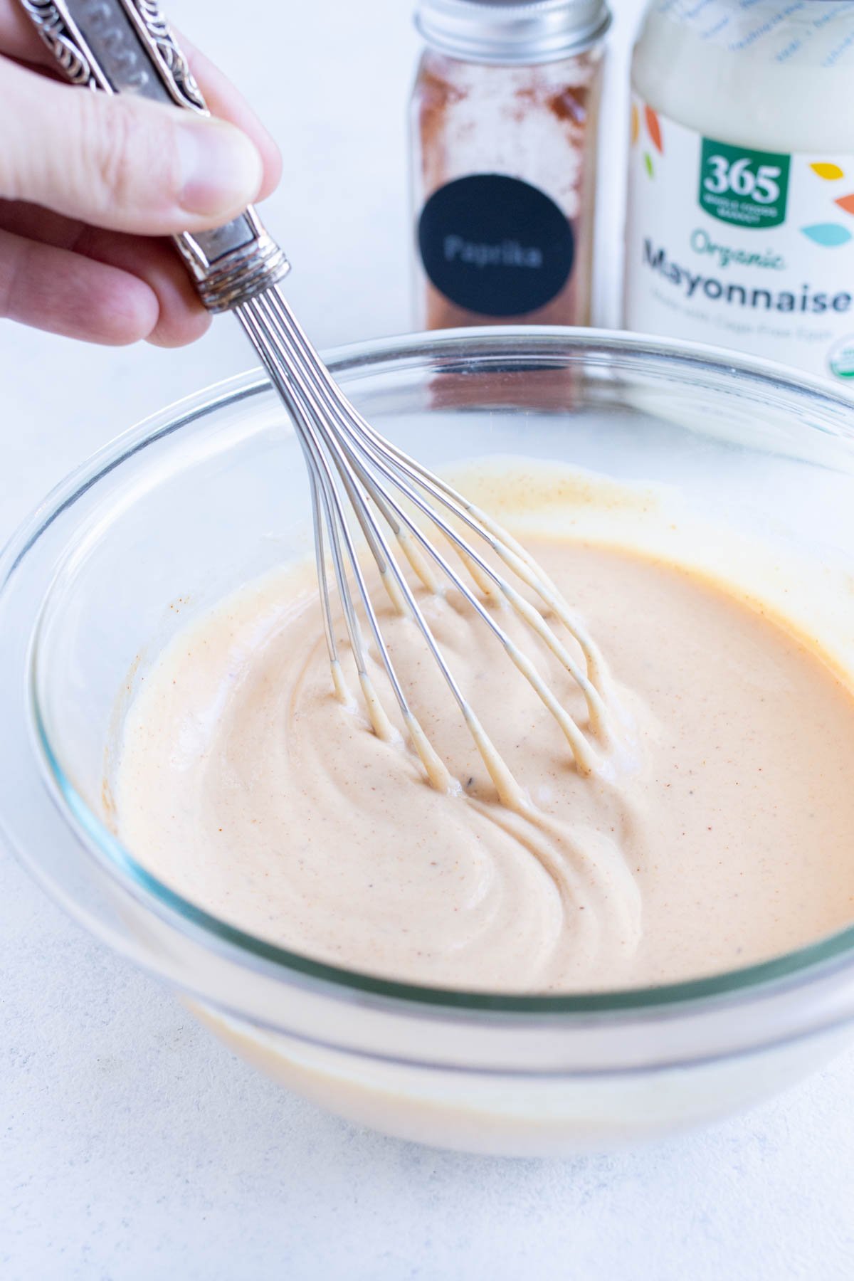 Creamy sauce is whisked together in a glass bowl.