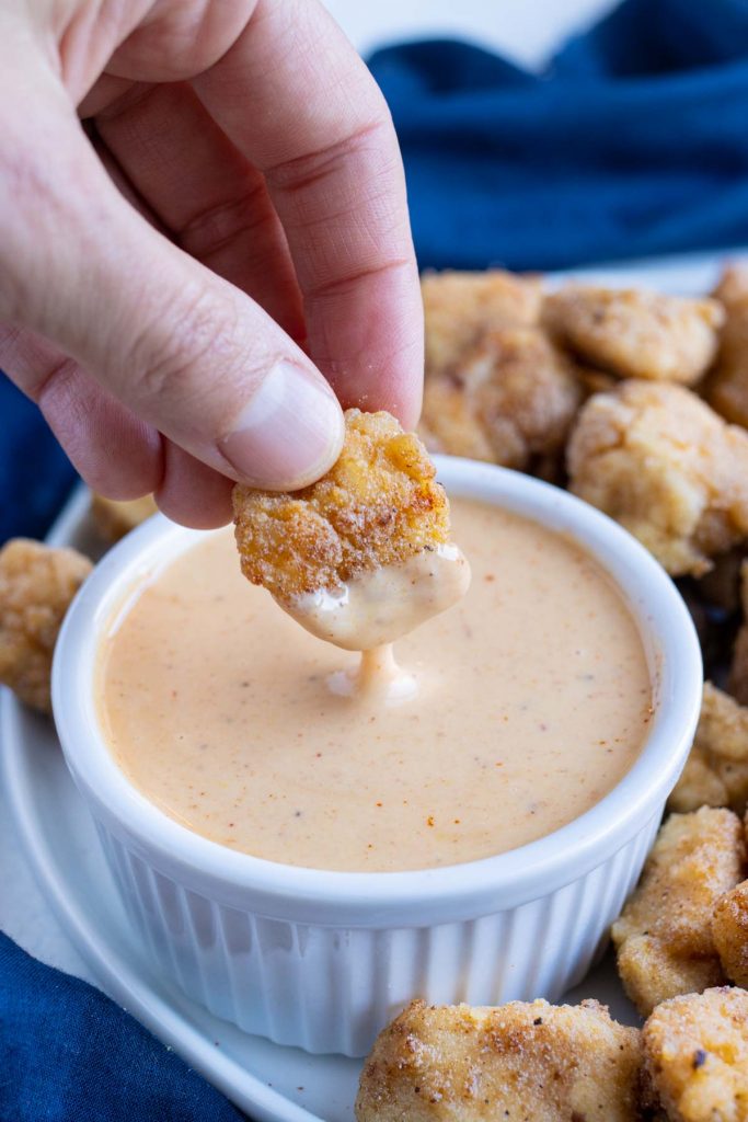 A chicken nugget is dipped into the Chick-fil-A sauce.