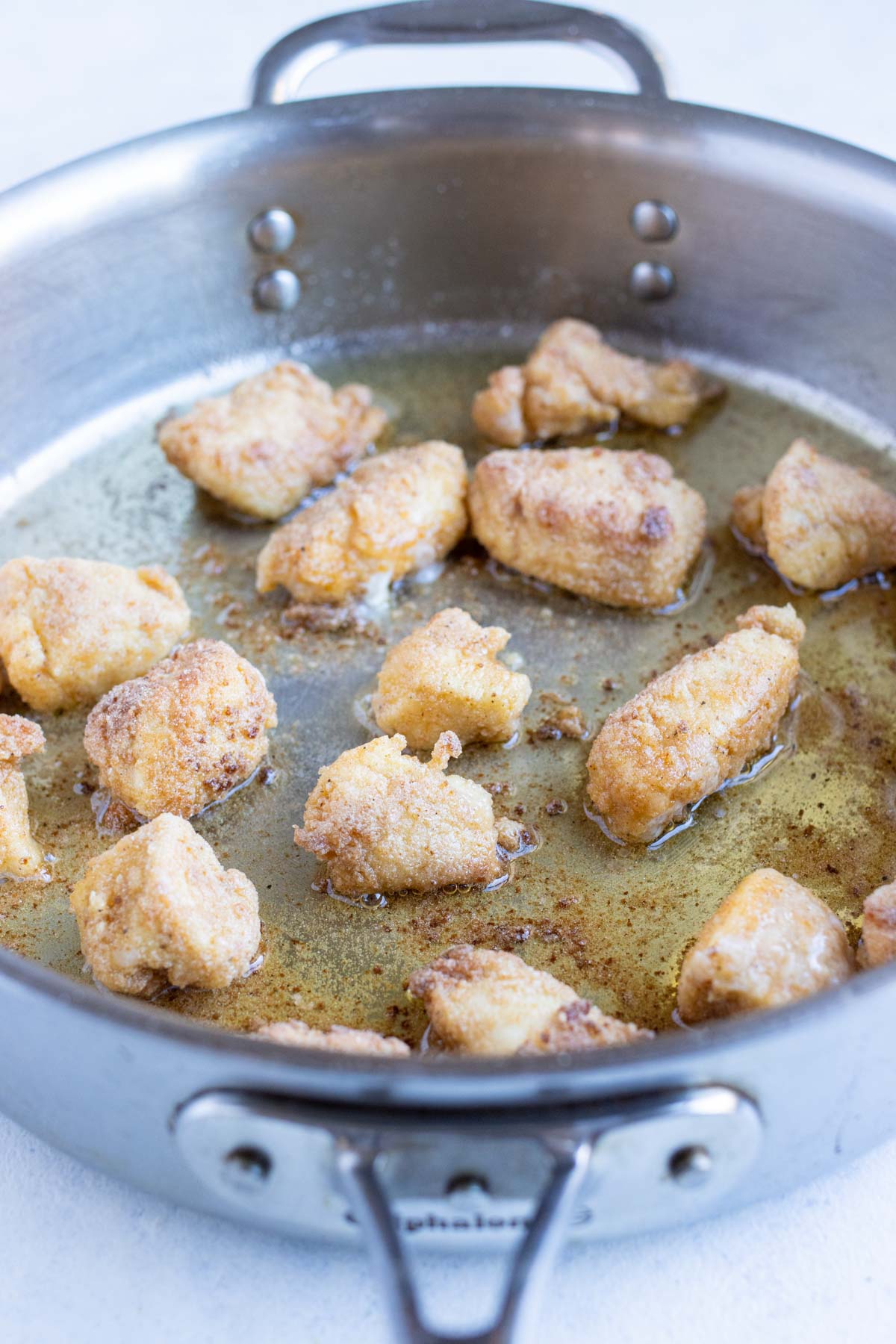 Bread nuggets are cooked on the stove in a pan.