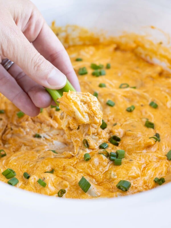 Celery is dipped into the slow cooker buffalo dip for an appetizer.