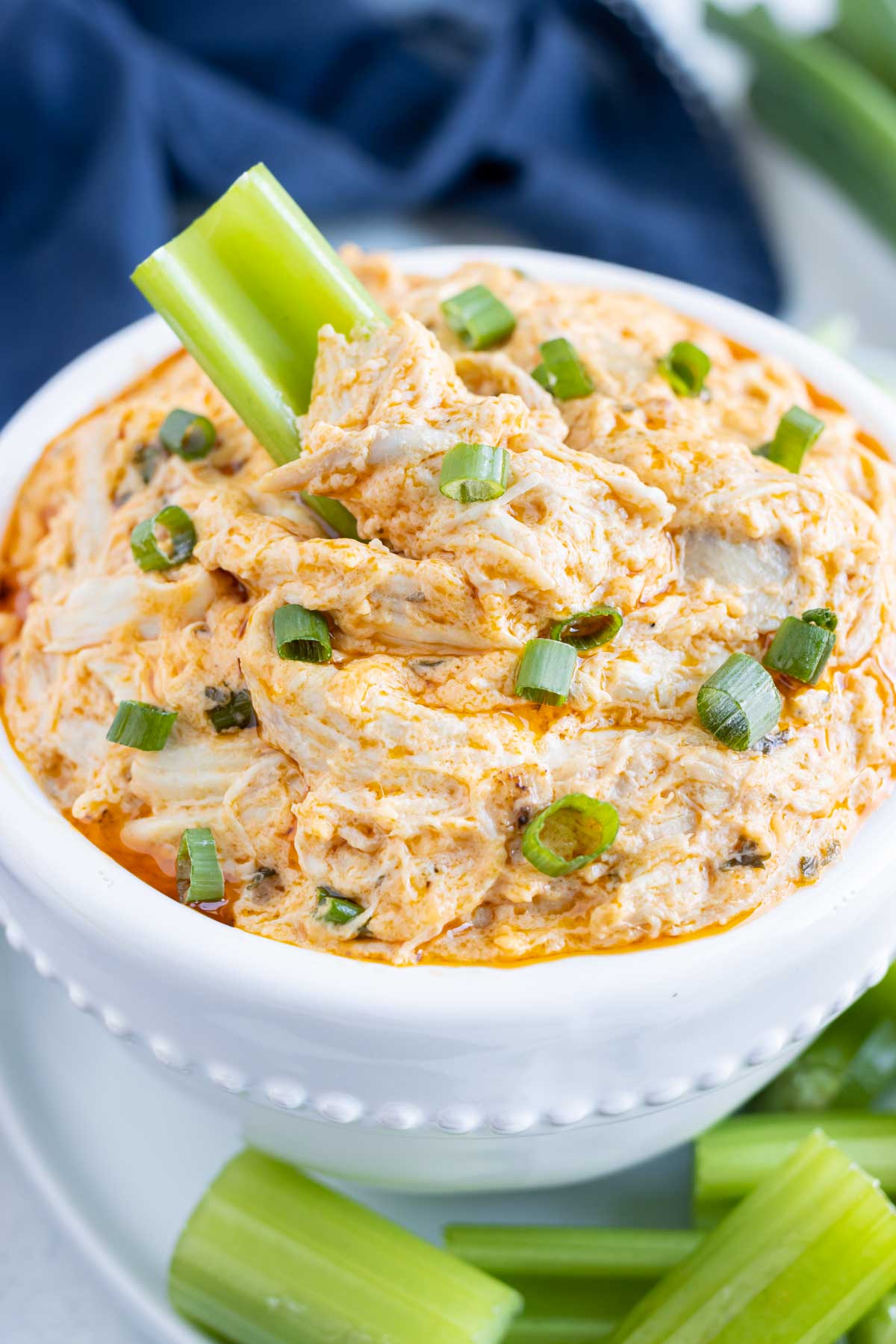 A bowl of low-carb buffalo chicken dip is eaten with celery.