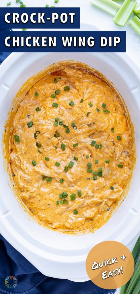 Slow cooker buffalo chicken dip is eaten with a piece of celery.