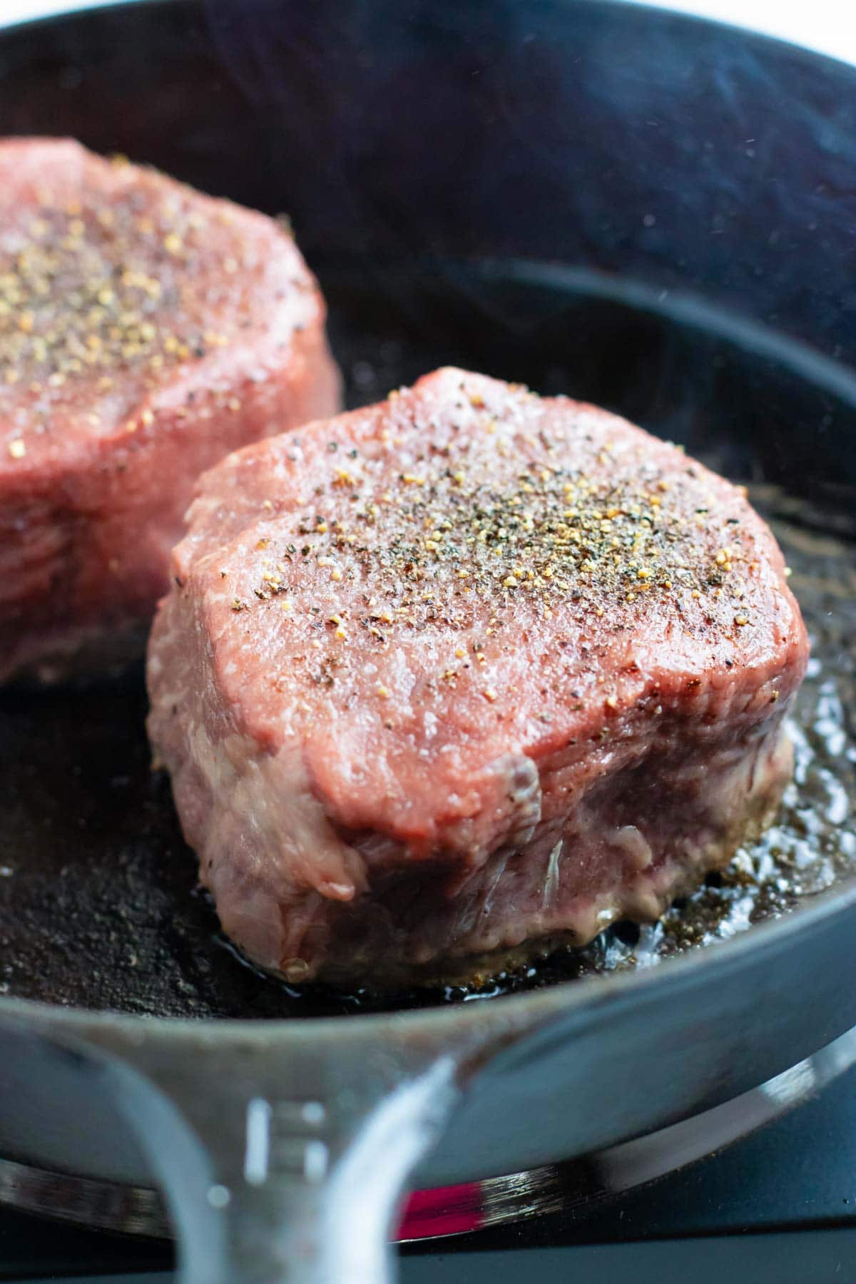 Pan-seared filet mignon in a cast iron skillet over high heat.