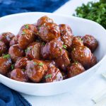 A bowl is filled with grape jelly meatballs .