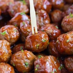 A toothpick is shown picking up a grape jelly meatball.