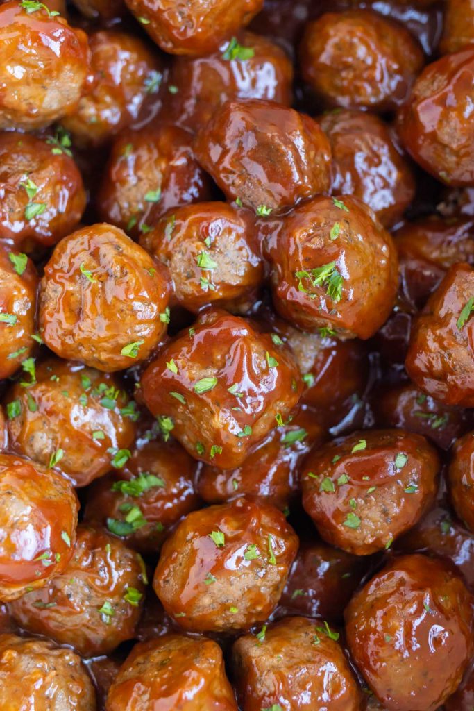 Tender grape jelly meatballs are garnished with parsley.