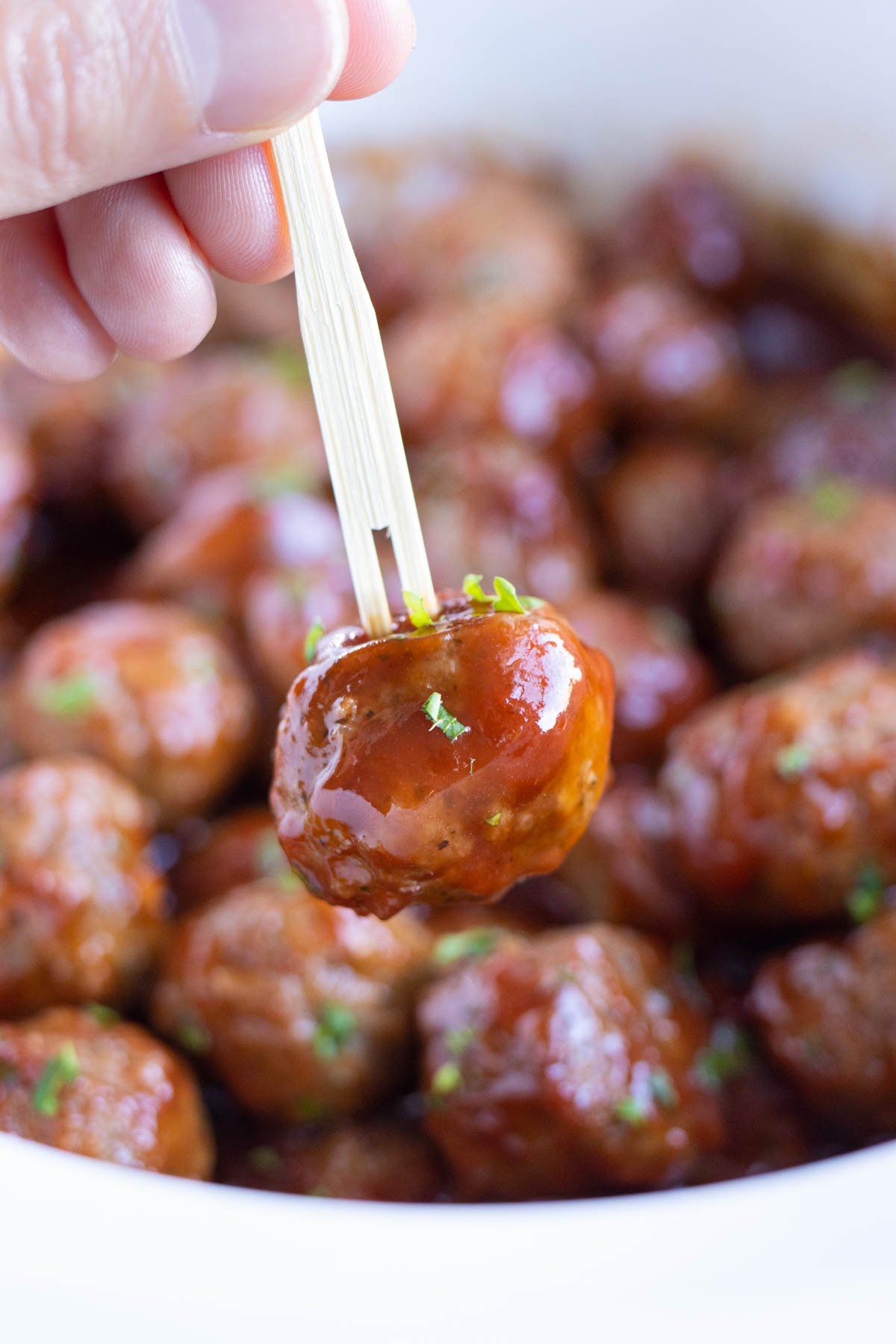 A toothpick is shown holding a meatball.