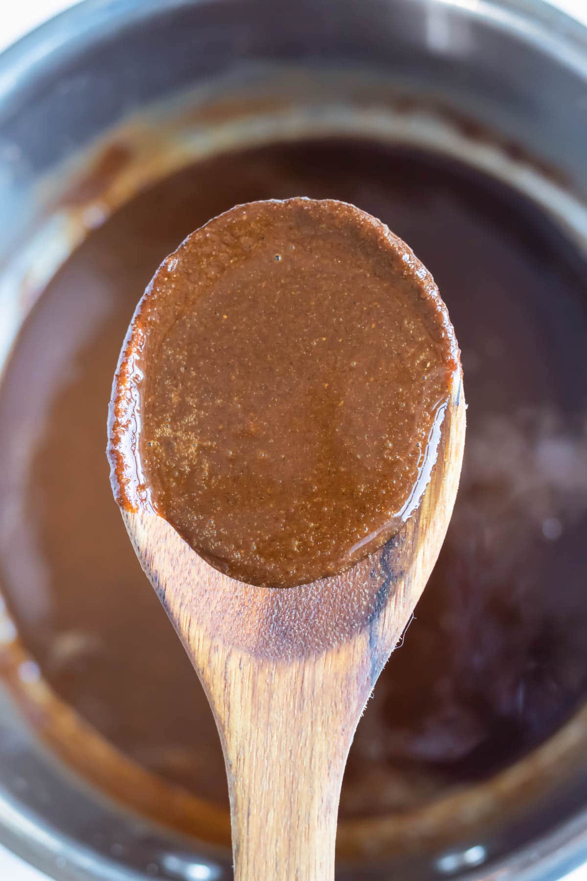 The roux is lifted out of the pot with a wooden spoon.