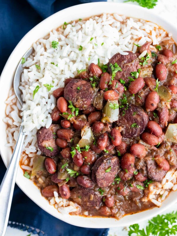 Instant pot red beans and rice are eaten with a spoon from a white bowl.